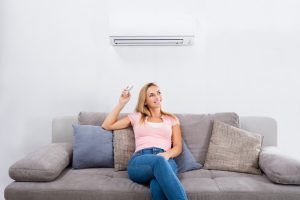 woman-sitting-on-couch-operating-ductless-air-handler